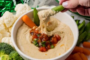 sugar snap pea dipped in cottage cheese queso surrounded by fresh vegetables