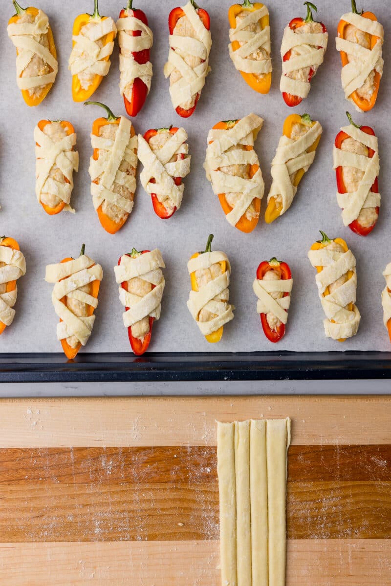 strips of puff pastry on a cutting board and peppers wrapped in puff pastry strips