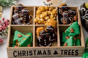 A wooden tray of Christmas cookies and popcorn displayed festively