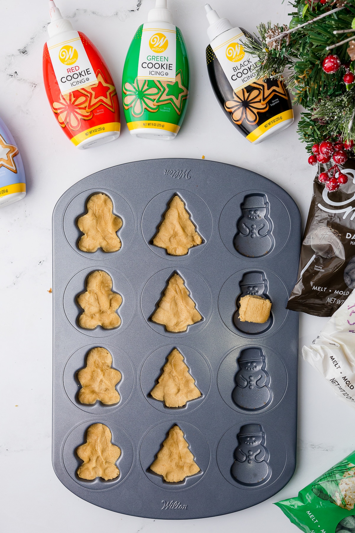 Wilton Christmas cookie pan with cookie dough pushed in and Wilton Icing Tubes