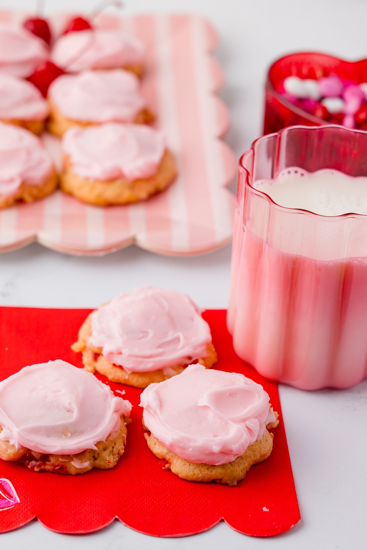 cherry cookies on a red valentine's day napkins with a glass of milk, cookies on a scalloped pink plate