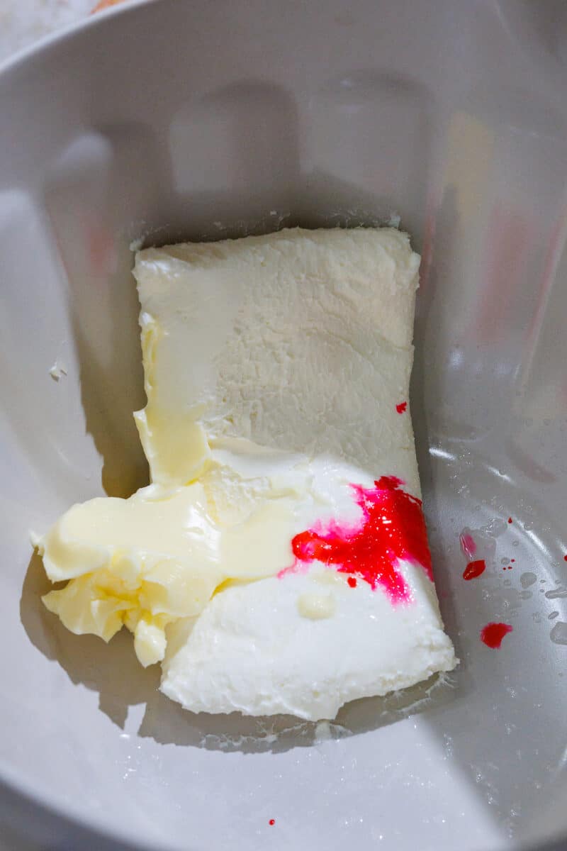 cream cheese, butter, almond extract, and food coloring in a batter bowl