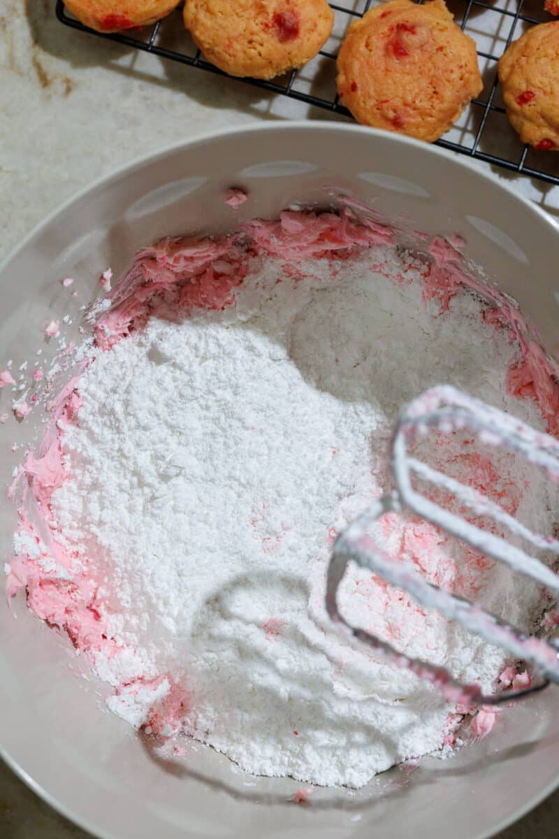 powdered sugar in a batter bowl with cherry cookies in the background