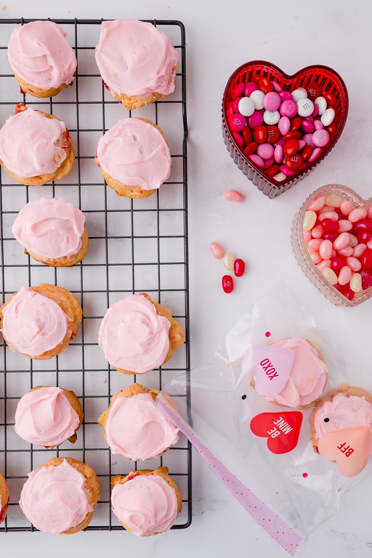 cherry cookies on a white cooling rack with pink frosting