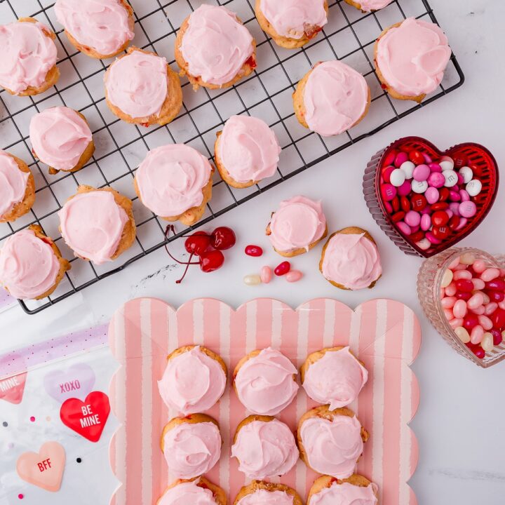 frosted cherry cookies on a scalloped plate, a wire cookie sheet, maraschino cherries, and heart shaped bowls full of candy