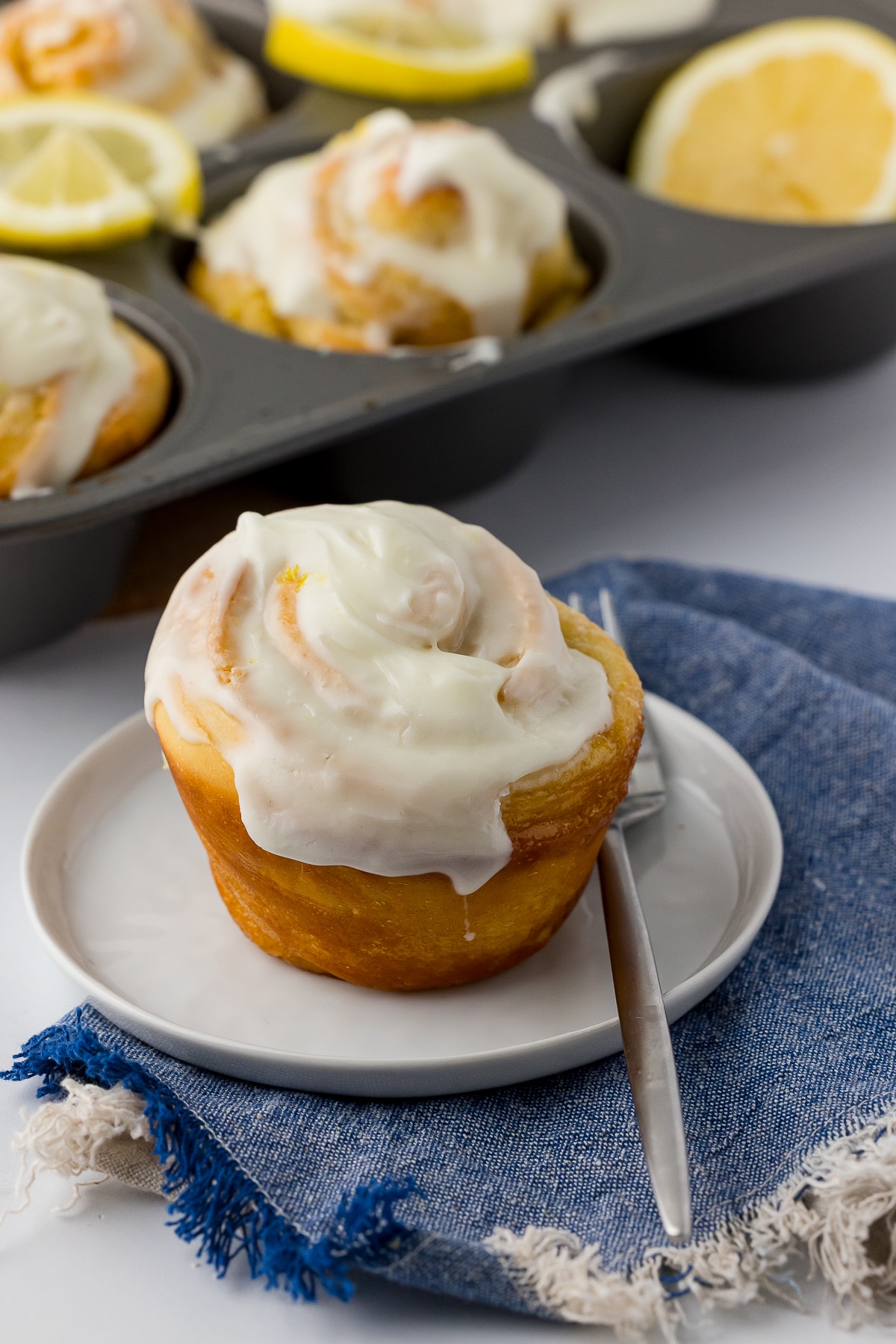 lemon roll on a white plate with a fork, on a blue napkin