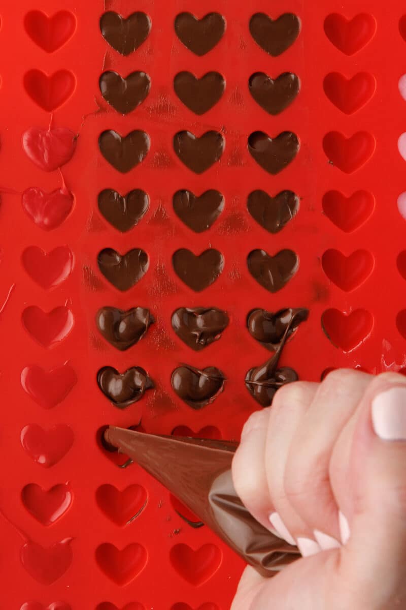 squeezing chocolate into a mini heart shaped mold