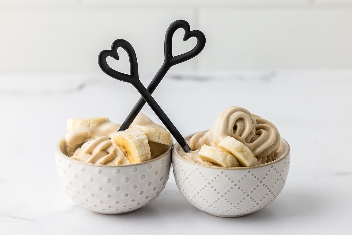 two bowls of frozen yogurt with bananas on a white countertop