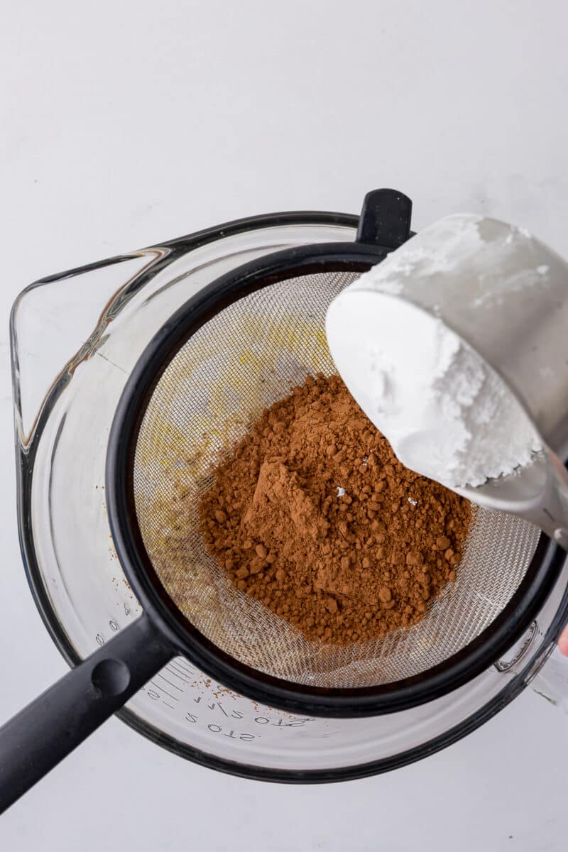 cocoa and powdered sugar in a strainer over a batter bowl