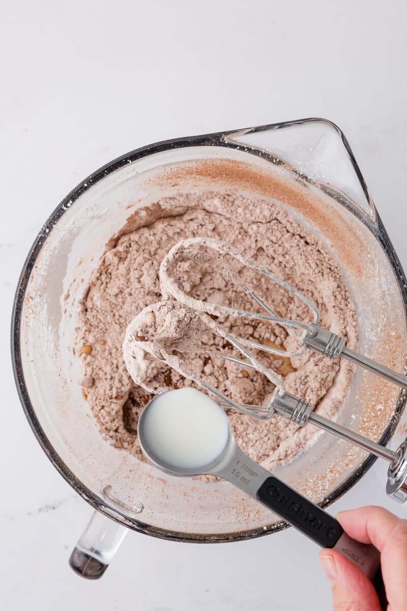 tablespoons of cream over a batter bowl filled with powdered sugar and cocoa