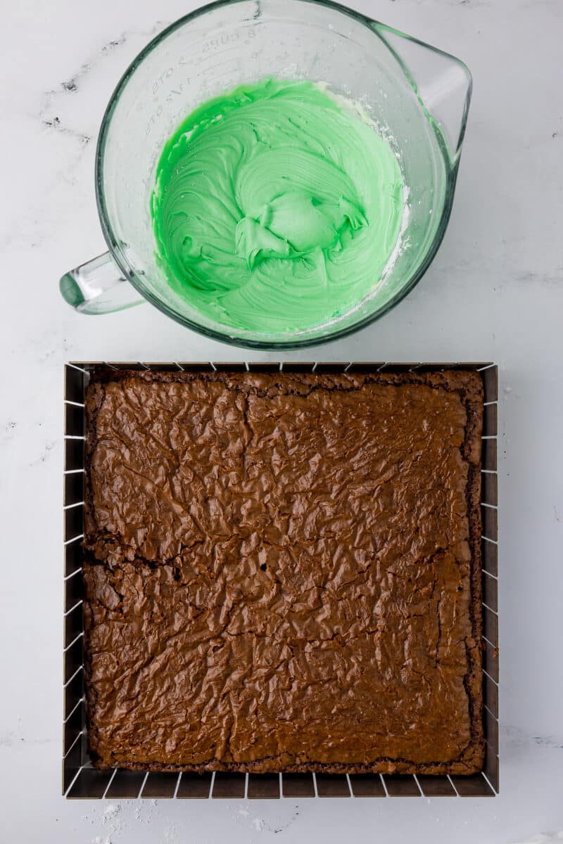 brownies in a pan and mint frosting in a batter bowl