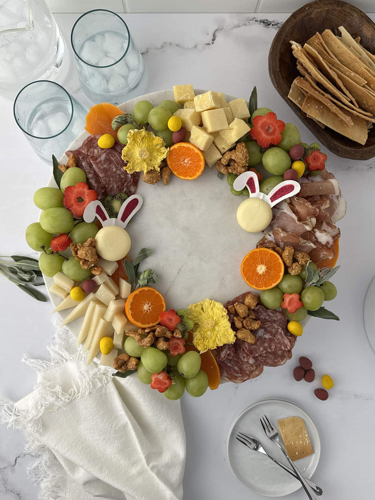 Fruit and meat tray shaped like a wreath on a table with napkins and crackers