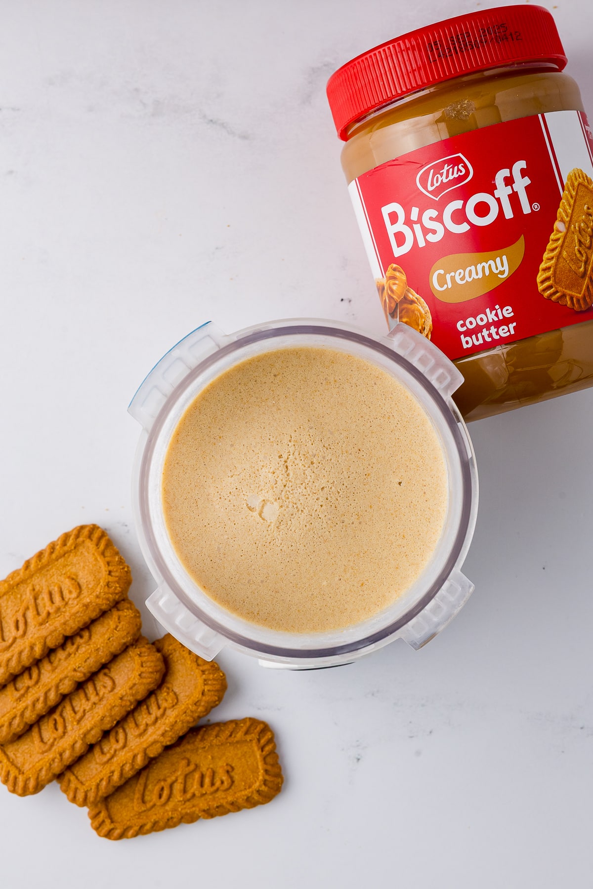 frozen biscoff ice cream in a ninja creami swirl pint jar with a jar of cookie butter and 5 biscoff cookies
