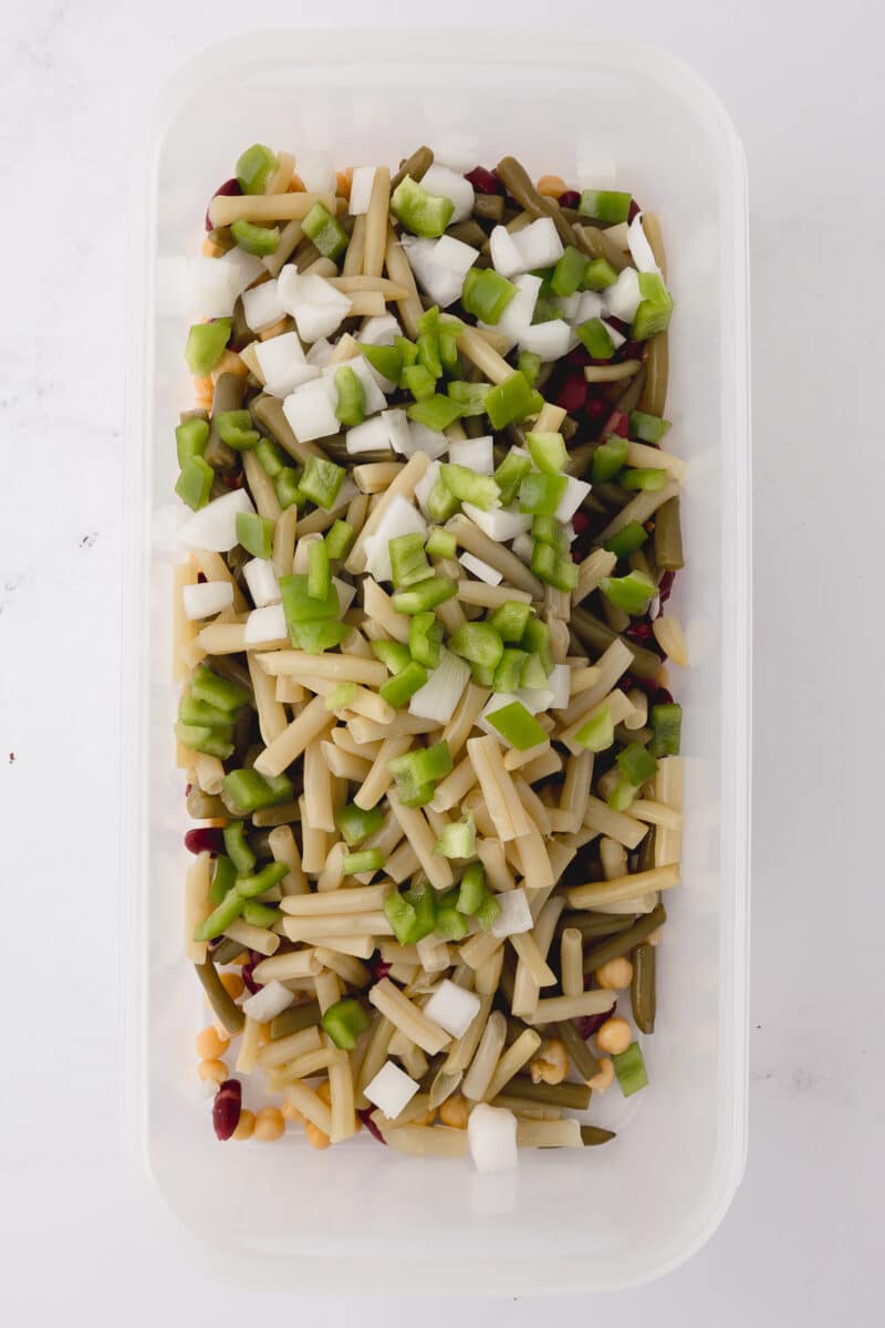 tupperware rectangular dish with beans, onions, and green peppers on a white countertop