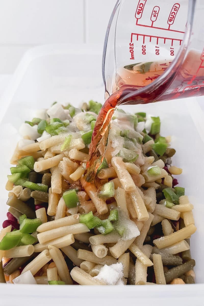 pouring red wine vinegar into three bean salad