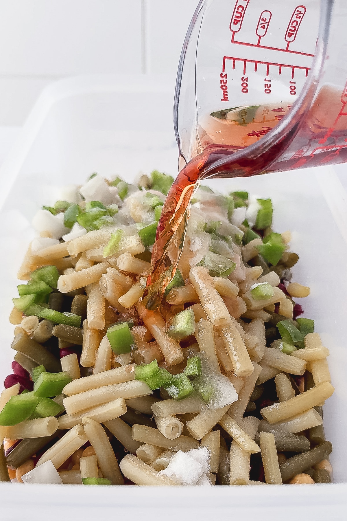 pouring red wine vinegar into three bean salad