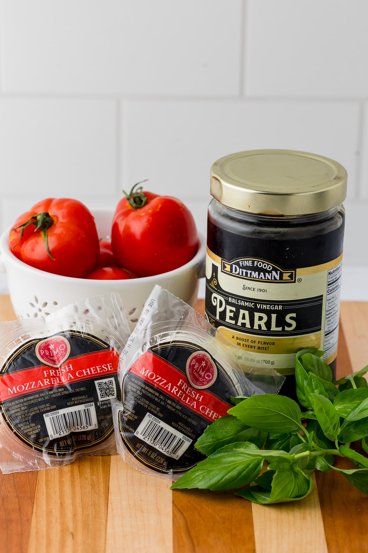 Jar of Dittmann's Balsamic Vinegar Pearls on a cutting board with mozzarella cheese and tomatoes and fresh basil