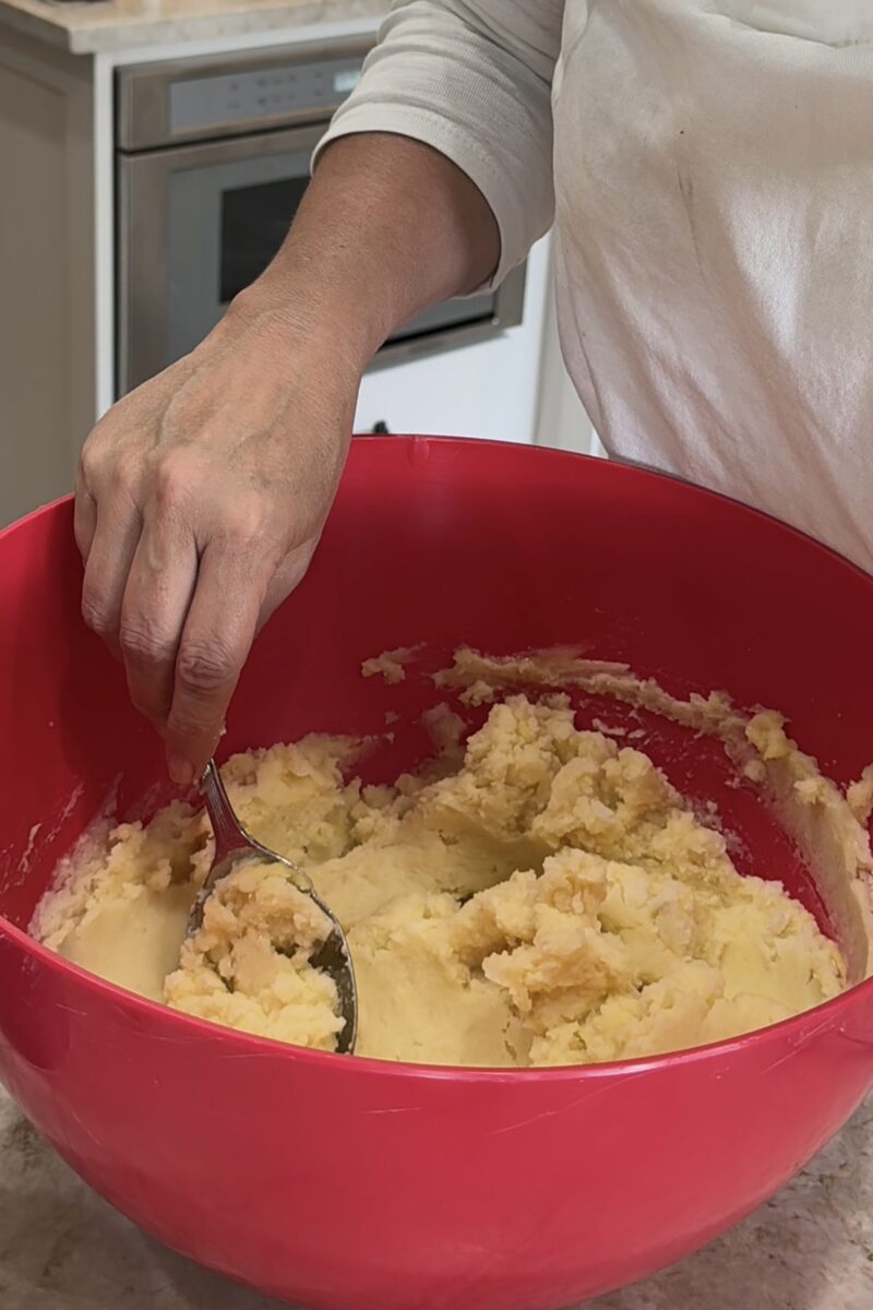 mixing gnocchi in a red bowl