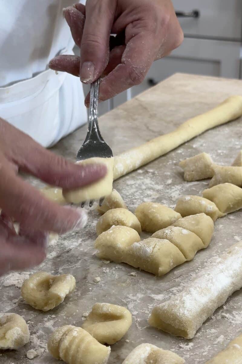 shaping gnocchis on a fork in a white kitchen