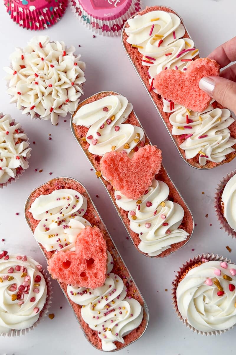 placing cake hearts on top of the frosting on mini loaf