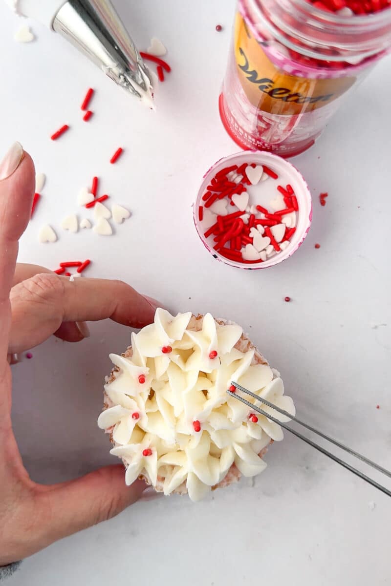 placing red sprinkles on hydrangea cupcake