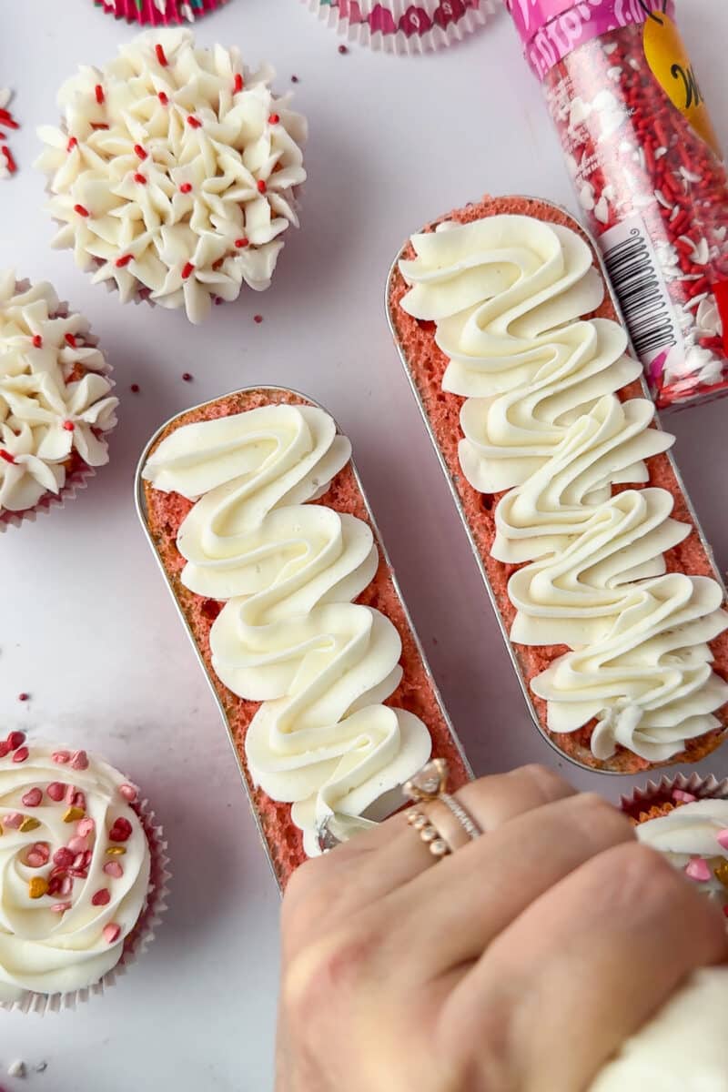 decorating mini loaf strawberry cake with white frosting
