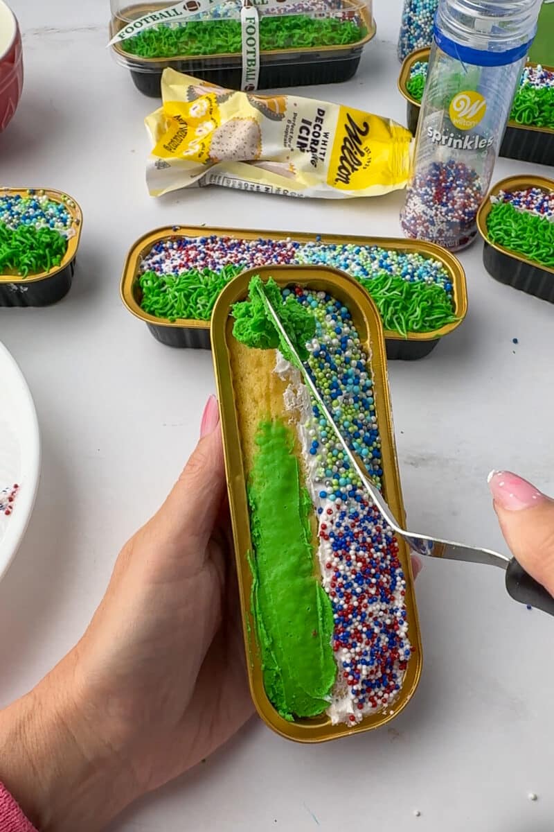 spreading green frosting on a mini loaf pan to resemble grass