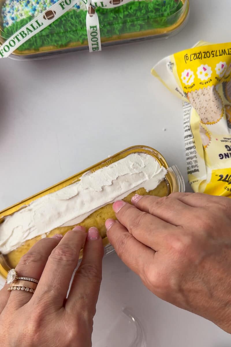 spreading white wilton frosting on a mini loaf pan on a white countertop
