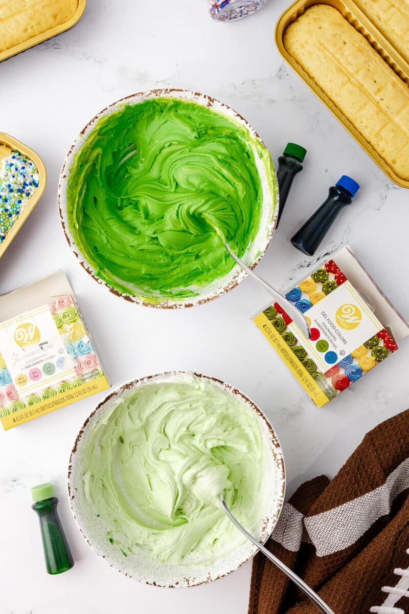 green frosting in a bowl with wilton food coloring on the counter