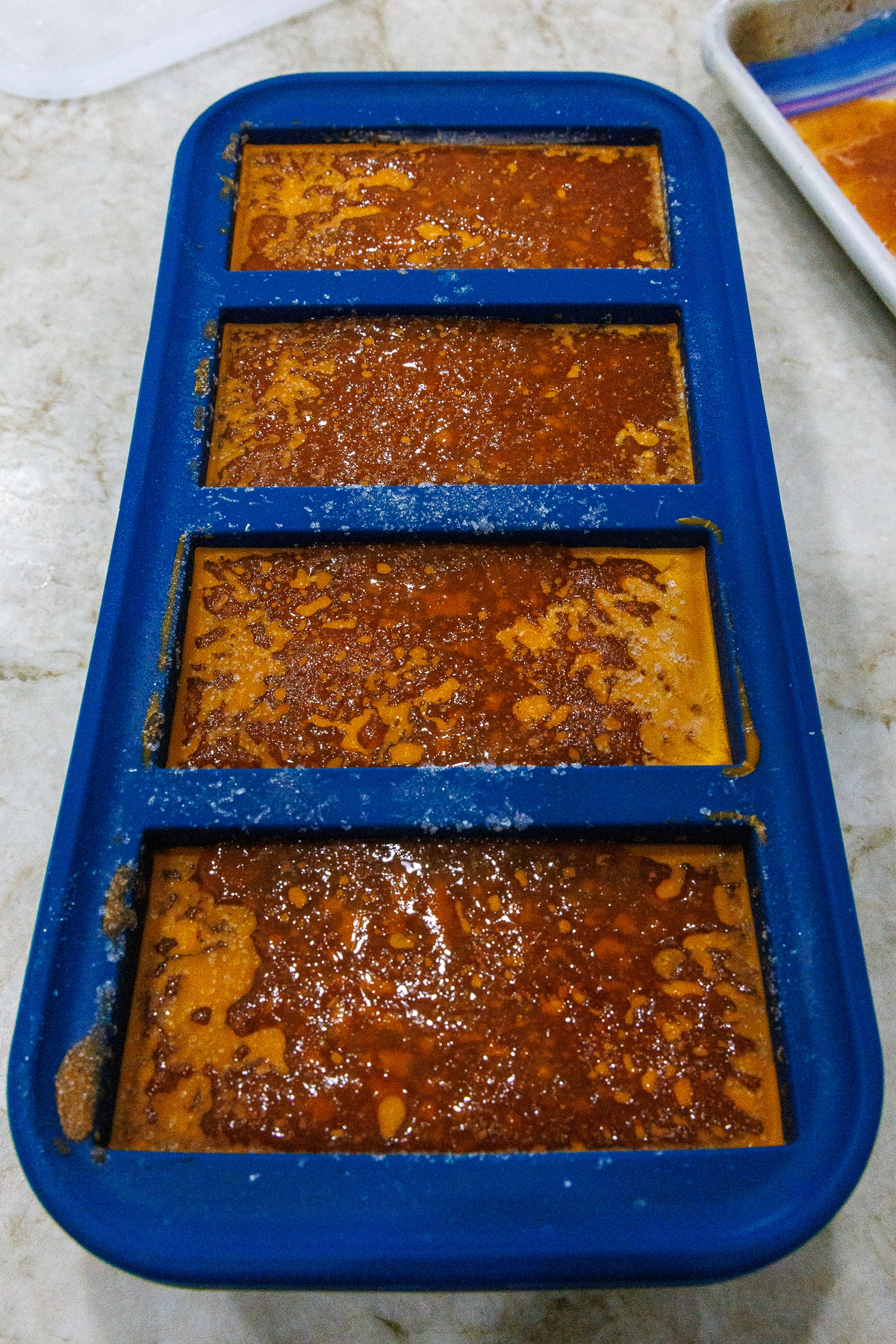 Frozen blocks of tomato sauce inside a blue silicone Souper Cubes tray.