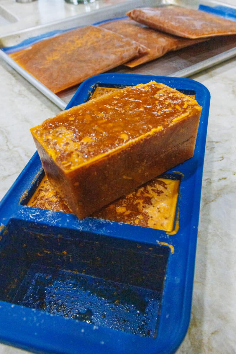 A large, rectangular frozen block of tomato sauce resting on top of its blue silicone freezing tray.