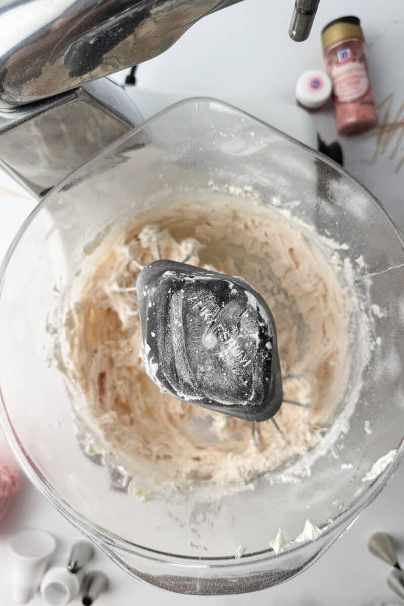 Creamy whipped butter in a mixer bowl with a light dusting of strawberry powdered sugar.