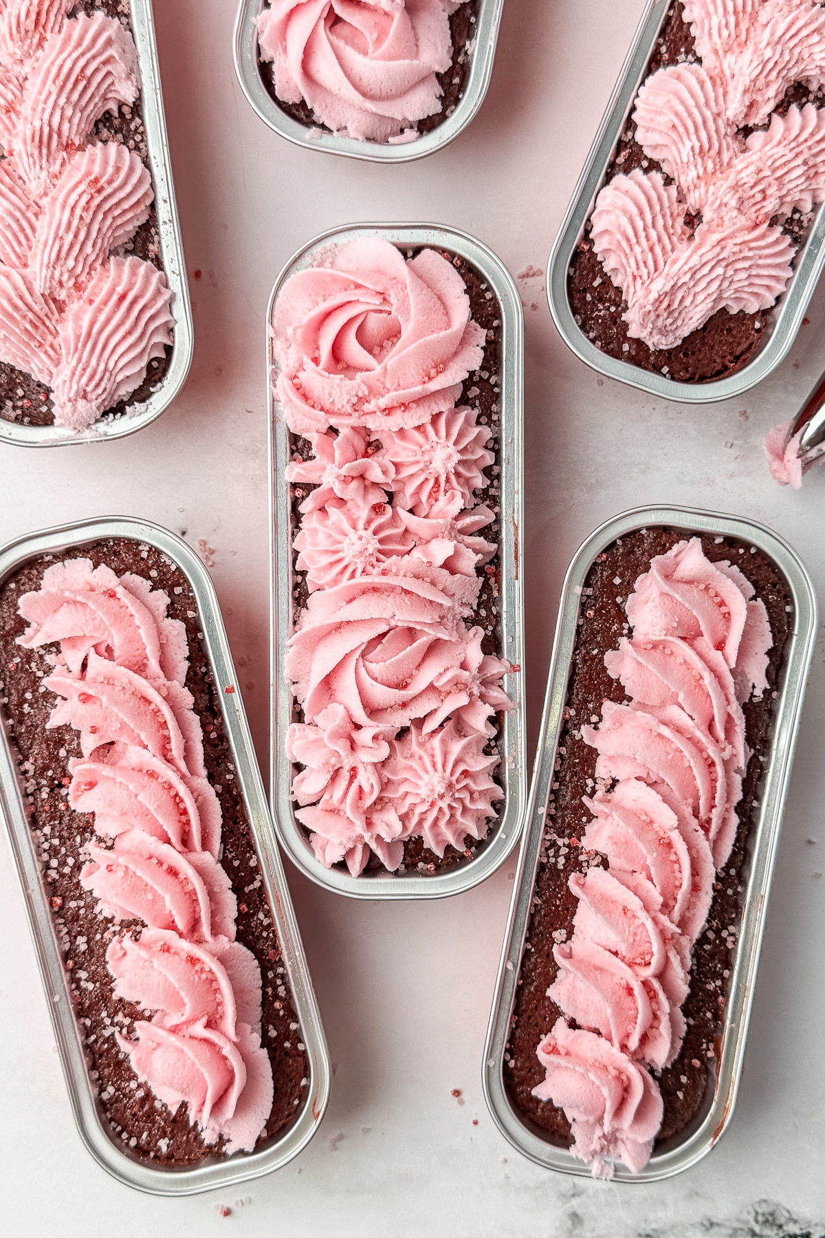 Top-down shot of beautifully piped strawberry buttercream loaves styled with a red "LOVE" gift tag.