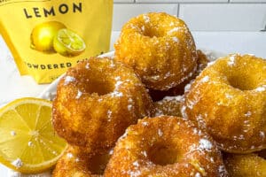 Close-up of mini lemon drizzle bundt cakes dusted with powdered sugar, with a Whipzi lemon sugar bag in the background.