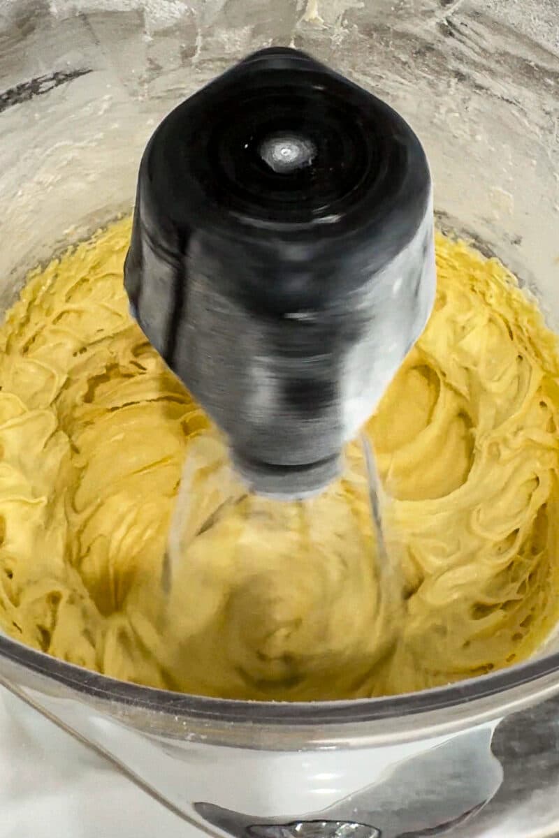 A stand mixer blending the rich, smooth lemon cake batter until fully incorporated and ready for the mini bundt pans.