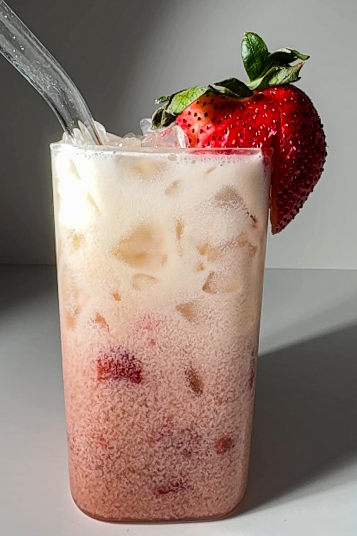 A finished Strawberry Lemon Poppi Dirty Soda with a fresh strawberry garnish on the rim.
