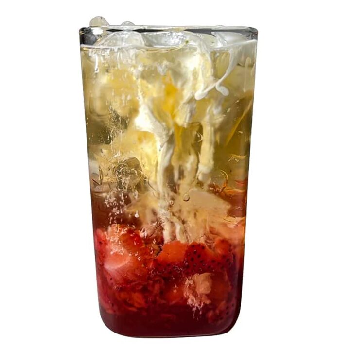 Heavy cream swirling into a Strawberry Lemon Poppi soda, creating a marbled effect.