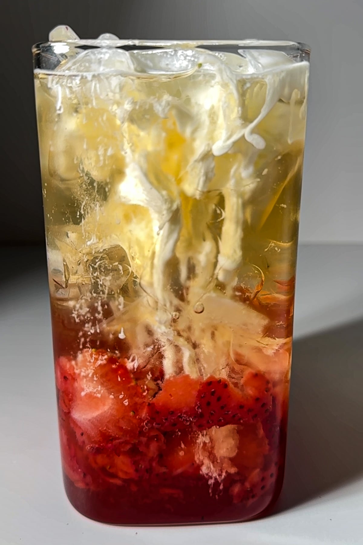 Heavy cream swirling into a Strawberry Lemon Poppi soda, creating a marbled effect.